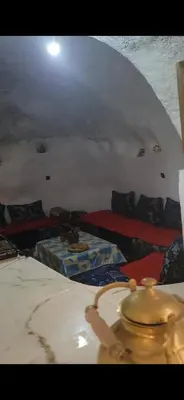 a room with a bed and a table in a room at Yamna Cozy Cave in Bhalil