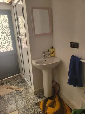 a bathroom with a white sink and a shower at Yamna Cozy Cave in Bhalil