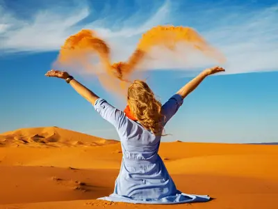 a woman in the desert with her arms outstretched at Merzouga Soul Camp in Merzouga