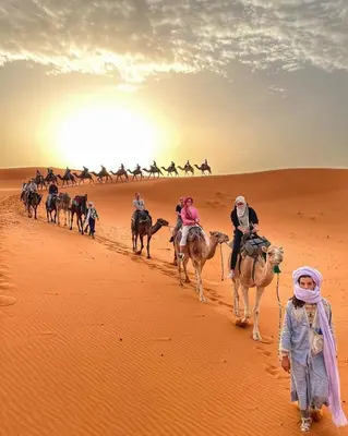 a group of people riding camels in the desert at Merzouga Soul Camp in Merzouga