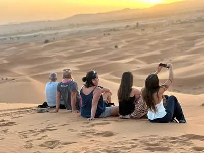 a group of people sitting on the sand in the desert at Merzouga Soul Camp in Merzouga