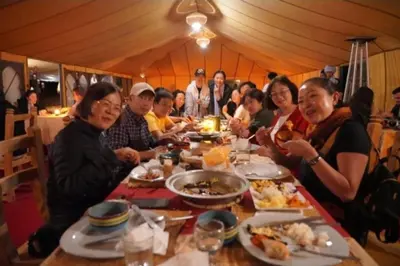 a group of people sitting at a table eating food at Merzouga Soul Camp in Merzouga