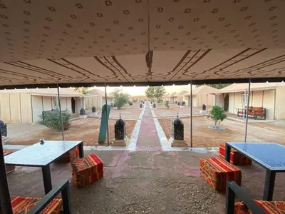 a group of tables and benches under a tent at Merzouga Soul Camp in Merzouga
