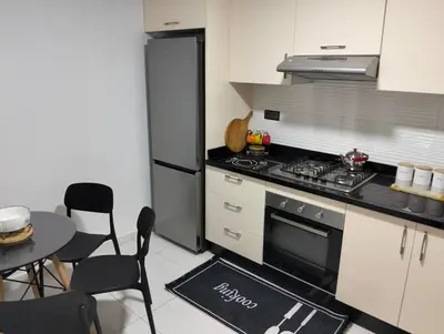 a kitchen with a stove and a table with chairs at Apartment Sea view Toudert Anza Agadir in Oulad Akkou