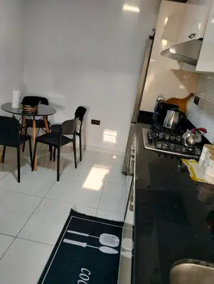 a kitchen with a stove and a table with chairs at Apartment Sea view Toudert Anza Agadir in Oulad Akkou