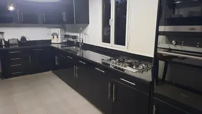 a kitchen with black cabinets and a stove top oven at Villa Roseaux heated pool Marrakech in Najem