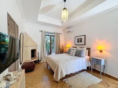 a white bedroom with a bed and a fireplace at Villa Paschmina, petit-déjeuner inclus in Ourika