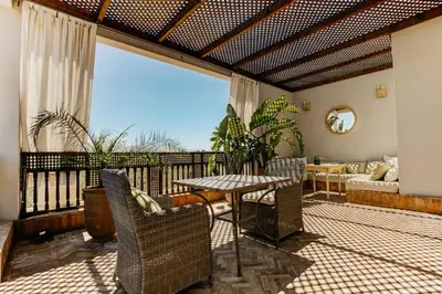 a living room with a table and chairs on a balcony at Villa Paschmina, petit-déjeuner inclus in Ourika
