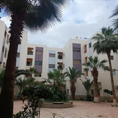 a building with palm trees in front of it at Smart home oumnia in Fès