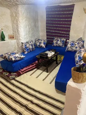 a living room with a blue couch and a table at كهوف يحيى لسياحة والمبيت البهاليل in Bhalil