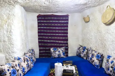 a room with blue and white pillows and a table at كهوف يحيى لسياحة والمبيت البهاليل in Bhalil