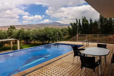 a patio with a table and chairs next to a swimming pool at Villa Atlas View in Aghmat