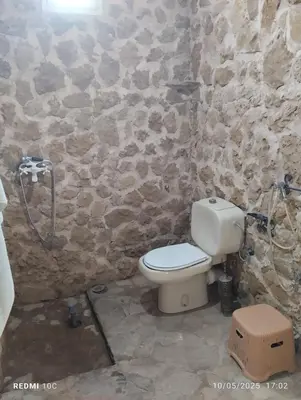 a bathroom with a toilet and a stone wall at Authentic Guesthouse with Garden and Mountain View Beni Mellal in Beni Mellal