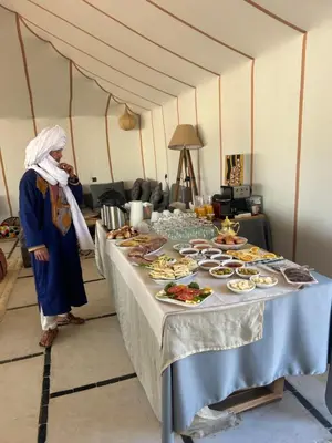 a woman standing in front of a table of food at Aurora Dunes Camp in Merzouga