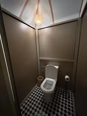 a small bathroom with a toilet with a checkered floor at Aurora Dunes Camp in Merzouga