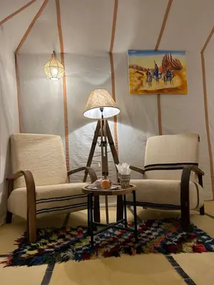 a living room with two chairs and a table at Aurora Dunes Camp in Merzouga