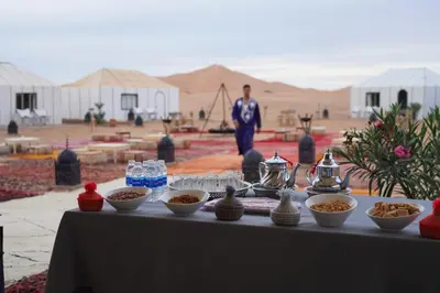 a table with bowls of food on it in the desert at Aurora Dunes Camp in Merzouga