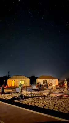 a group of tents on the beach at night at Aurora Dunes Camp in Merzouga