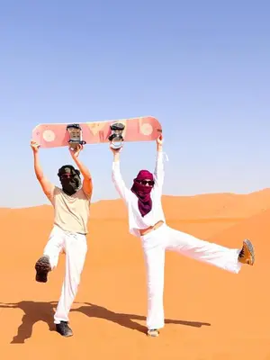 two men holding up a skateboard in the desert at dreaming desert Luxury Camp in Hassilabied