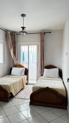two beds in a room with a window at Appartement spacieux à Agadir in Oulad Akkou