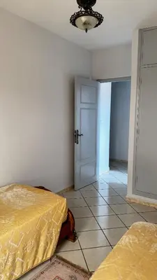 a bedroom with two beds and a room with a door at Appartement spacieux à Agadir in Oulad Akkou