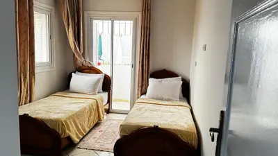 a small room with two beds and a window at Appartement spacieux à Agadir in Oulad Akkou