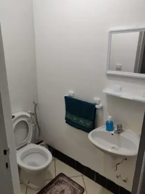 a white bathroom with a toilet and a sink at Appartement spacieux à Agadir in Oulad Akkou