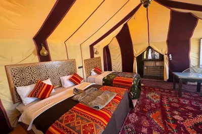 a bedroom with two beds in a tent at luxury desert night camp in Merzouga