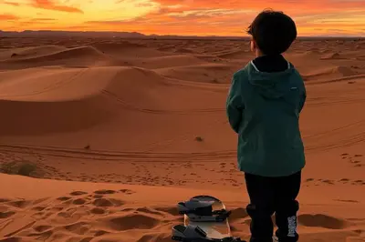 a young boy standing in the desert at sunset at luxury desert night camp in Merzouga