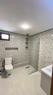 a bathroom with a toilet and a glass shower at Appartement Al Arz Atlas in Ifrane