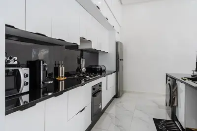 a kitchen with white cabinets and black appliances at Villa Ramona, Calme, Luxe et Piscine in Marrakech
