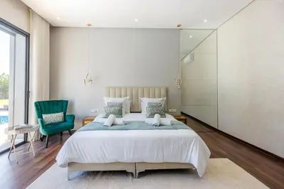 a bedroom with a large bed and a green chair at Villa Ramona, Calme, Luxe et Piscine in Marrakech