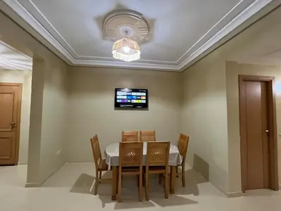a dining room with a table and chairs and a television at Appartement de 3 chambres pour 6 voyageurs à 20 minutes de centre ville de Marrakech in Azib Oulad Lâdem
