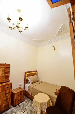 a small bedroom with a bed and a chair at DAR El Ghali in Fès