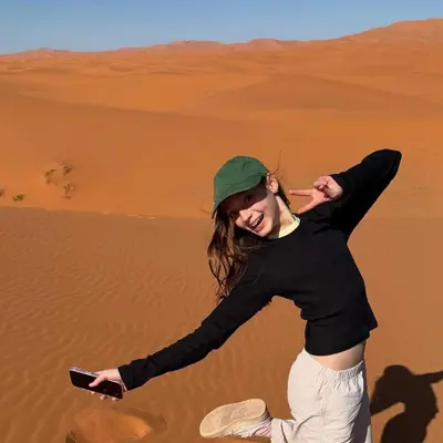 a woman in the desert holding a cell phone at Sand Fish Camp in Merzouga