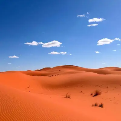 a desert with red sand and a blue sky at Sand Fish Camp in Merzouga