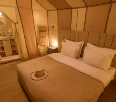 a bed with a hat sitting on top of it at Sud Est Camp in Merzouga