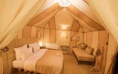 a bedroom with a bed and a couch in a tent at Sud Est Camp in Merzouga