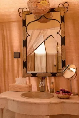 a bathroom with a sink with a large mirror at Sud Est Camp in Merzouga