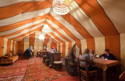 a group of people sitting at tables in a room at Sud Est Camp in Merzouga