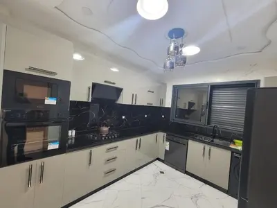a kitchen with white cabinets and black appliances at Bella Nova Air-Conditioned Apartment in Azrou