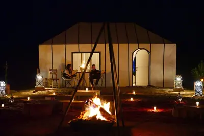 two people sitting around a fire in a tent at night at Starlit Desert Camp in Foum Zguid