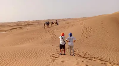 a group of people walking in the desert at Starlit Desert Camp in Foum Zguid