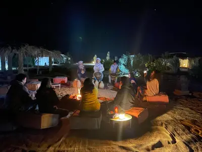 a group of people sitting around a fire at night at Siman luxury camp in Merzouga