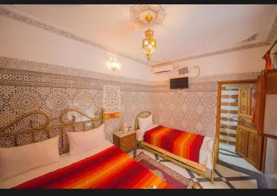 a bedroom with two beds and a chandelier at Riad Haddaji fez in Fès