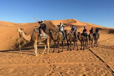 a group of people on camels in the desert at la petite maison du désert in Foum Zguid