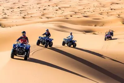 a group of people riding on atvs in the desert at la petite maison du désert in Foum Zguid