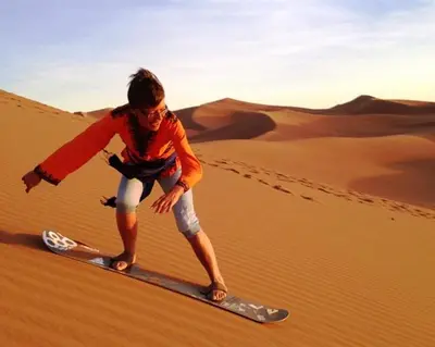 a woman on a surfboard in the desert at la petite maison du désert in Foum Zguid
