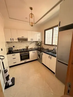 a kitchen with white cabinets and a stainless steel refrigerator at Chic & Cozy Apartment for a Comfortable Stay Fes in Fès