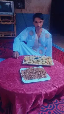 a man sitting at a table with a plate of food at Hassan's Guest House in Mhamid